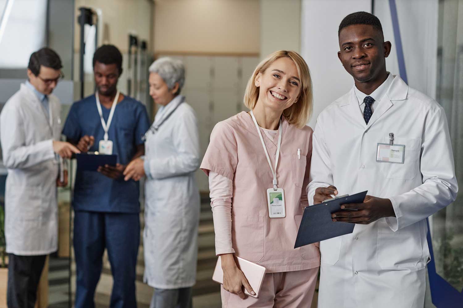 Diverse medical team with doctors and nurses smiling and discussing patient care in a hospital corridor.